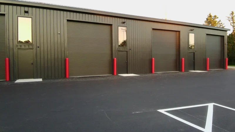 Row of The Shop units with drive-in garage doors and red bollards